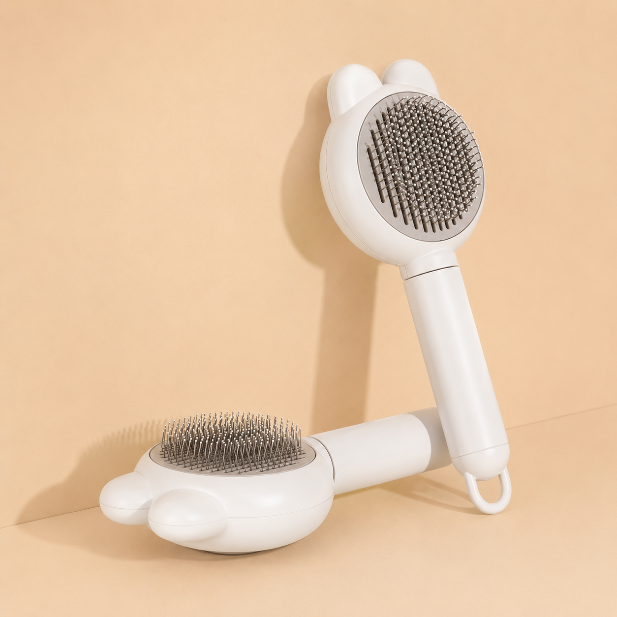 Miauva Cleaning Brush in ivory, two self-cleaning grooming brushes on a warm beige background